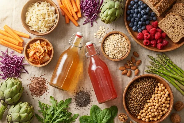 Bunte Auswahl darmfreundlicher pflanzlicher Lebensmittel — Sauerkraut, Kimchi, Kombucha, Beeren, Hafer, Hülsenfrüchte, Samen und Gemüse