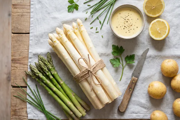 Flatlay mit weißem und grünem Spargel, veganer Hollandaise, Zitrone und Kartoffeln